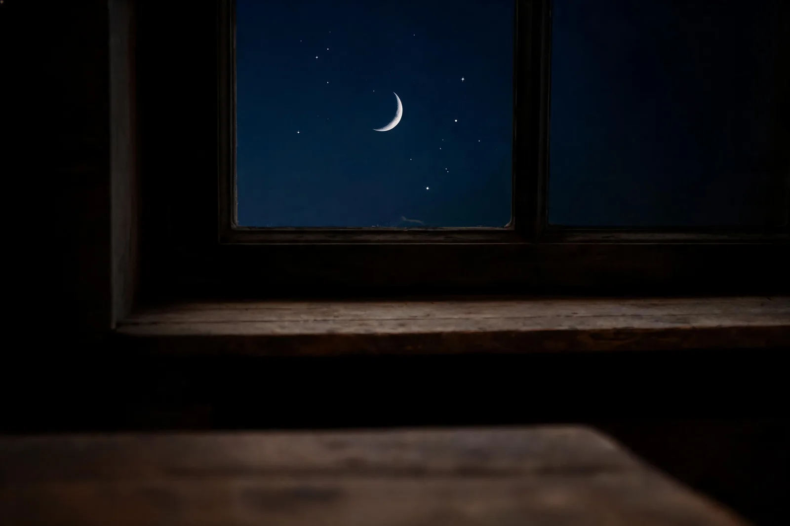 A single open window in a dark room at night, the night sky with a thin crescent moon and a few stars visible through the glass, the sill bare wood, jung synchronicity tarot threshold